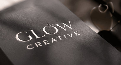 Dombornyomott, elegáns, fémes csillogású Glow Creative logó egy prémium minőségű, sötétszürke textúrájú papírtáskán.